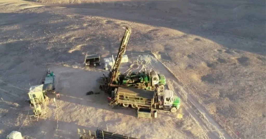 Plataforma de perforación minera operando en el desierto, con camiones y maquinaria instalada sobre terreno árido durante una faena de exploración.